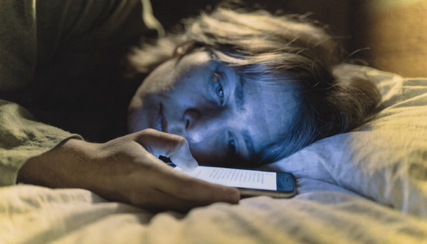A person lit by a phone screen in the dark